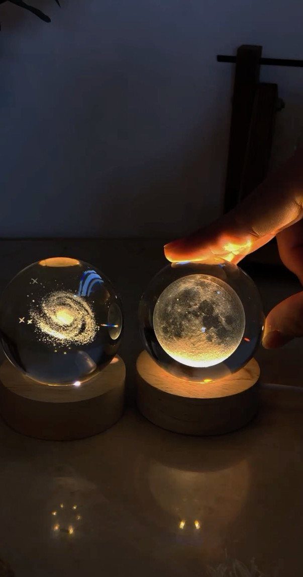 Two glowing glass sphere lamps, one showing a galaxy and one showing the moon.
