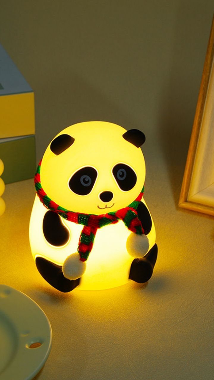 Panda-shaped LED night lamp wearing a red and green checkered scarf glowing warmly.