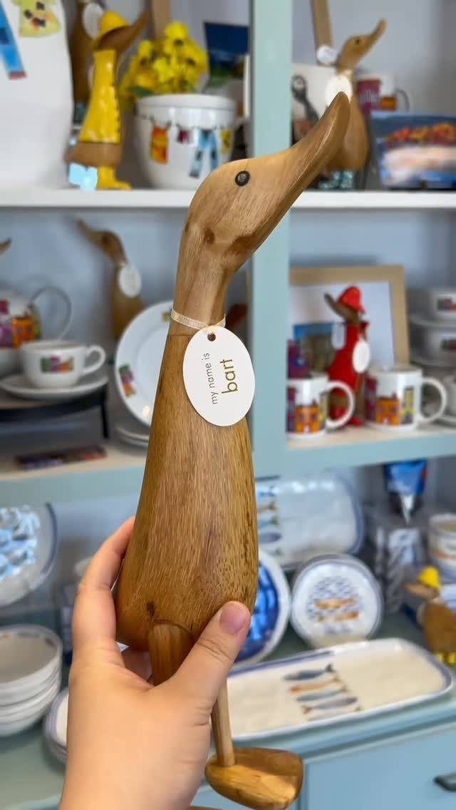 Hand-carved wooden duck figurine with a name tag held in a person's hand.