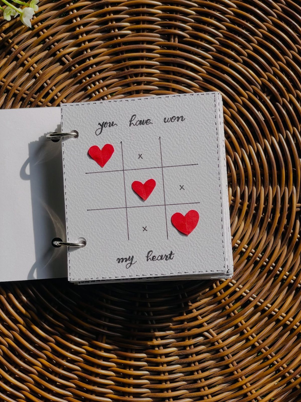 Handmade notebook page with a tic-tac-toe game using red hearts and romantic text.