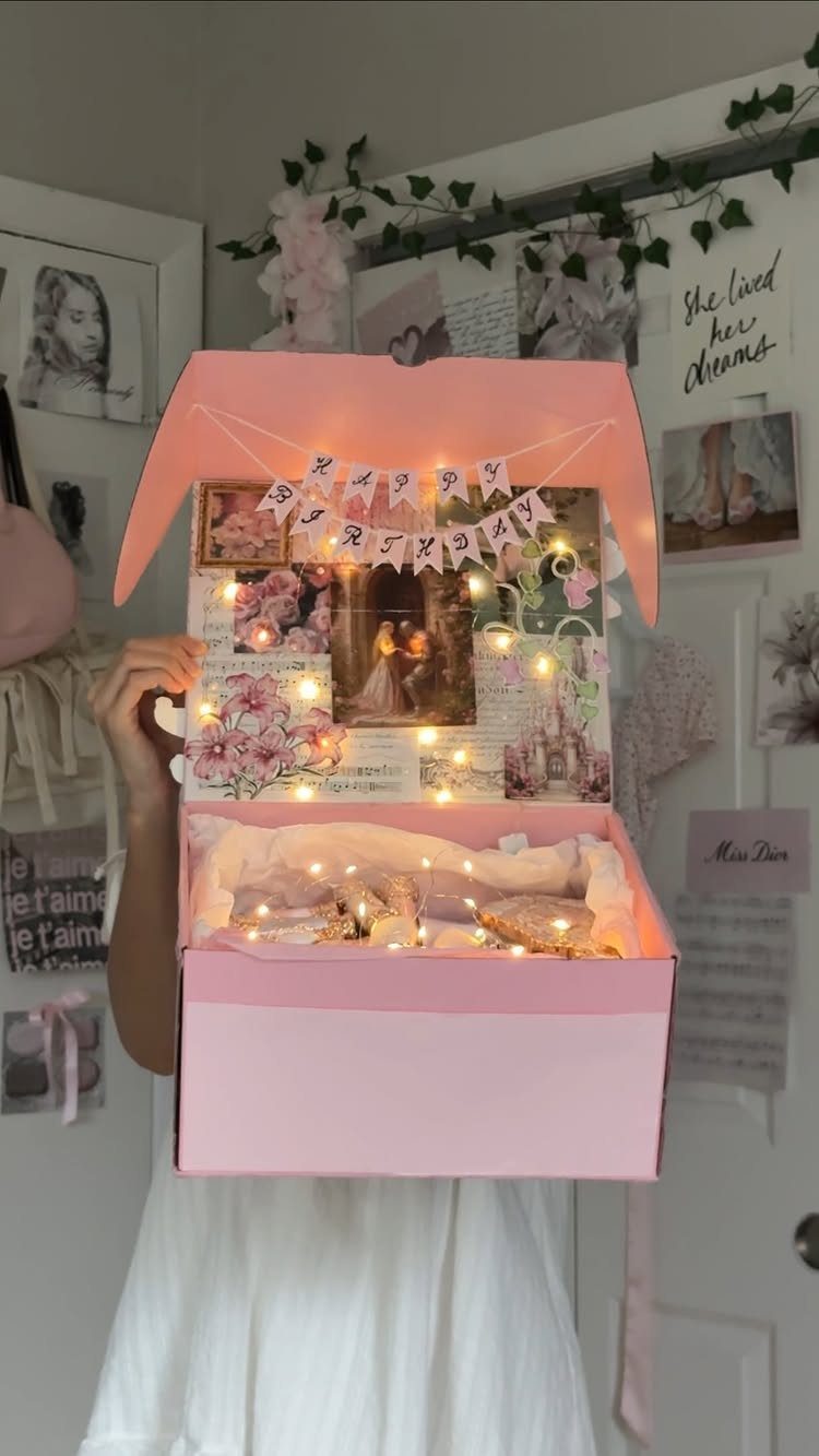 Open pink gift box with photos, fairy lights, and a birthday banner inside.