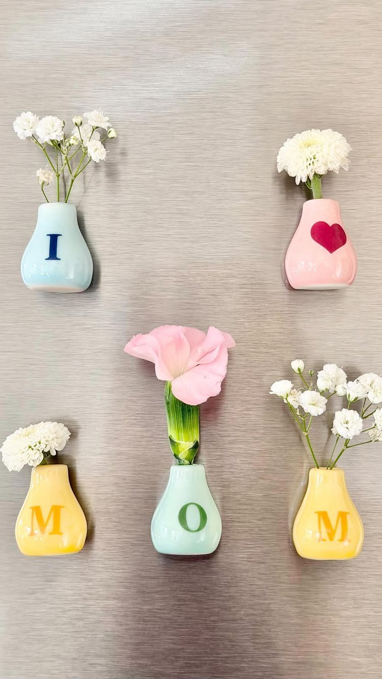 Small colorful vases with flowers spelling I LOVE MOM on a metal wall