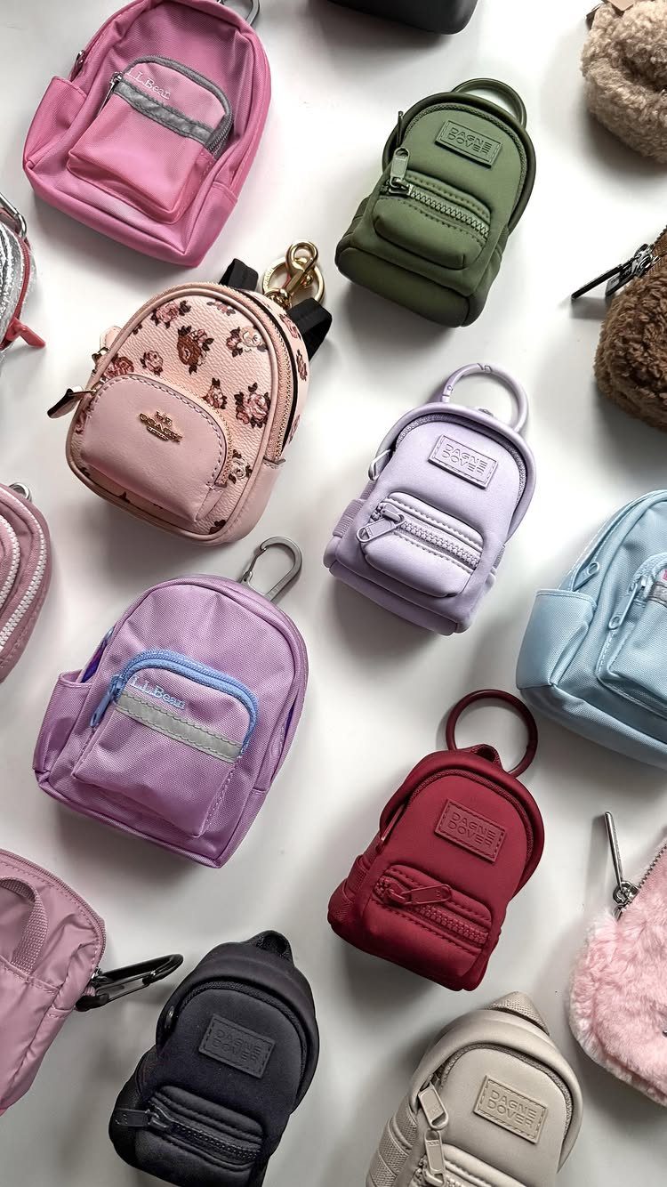 Miniature backpacks in various colors and styles arranged on a white background.