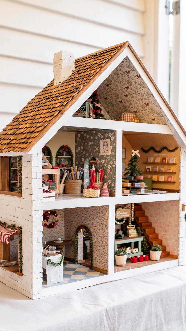 Miniature dollhouse decorated for Christmas with tiny trees and festive ornaments inside.