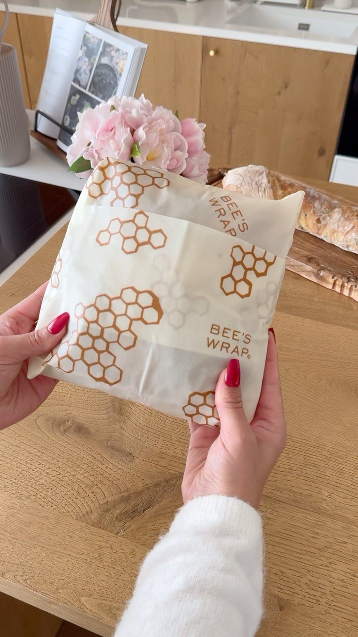 Beeswax food wrap with honeycomb patterns held by hands in a kitchen.
