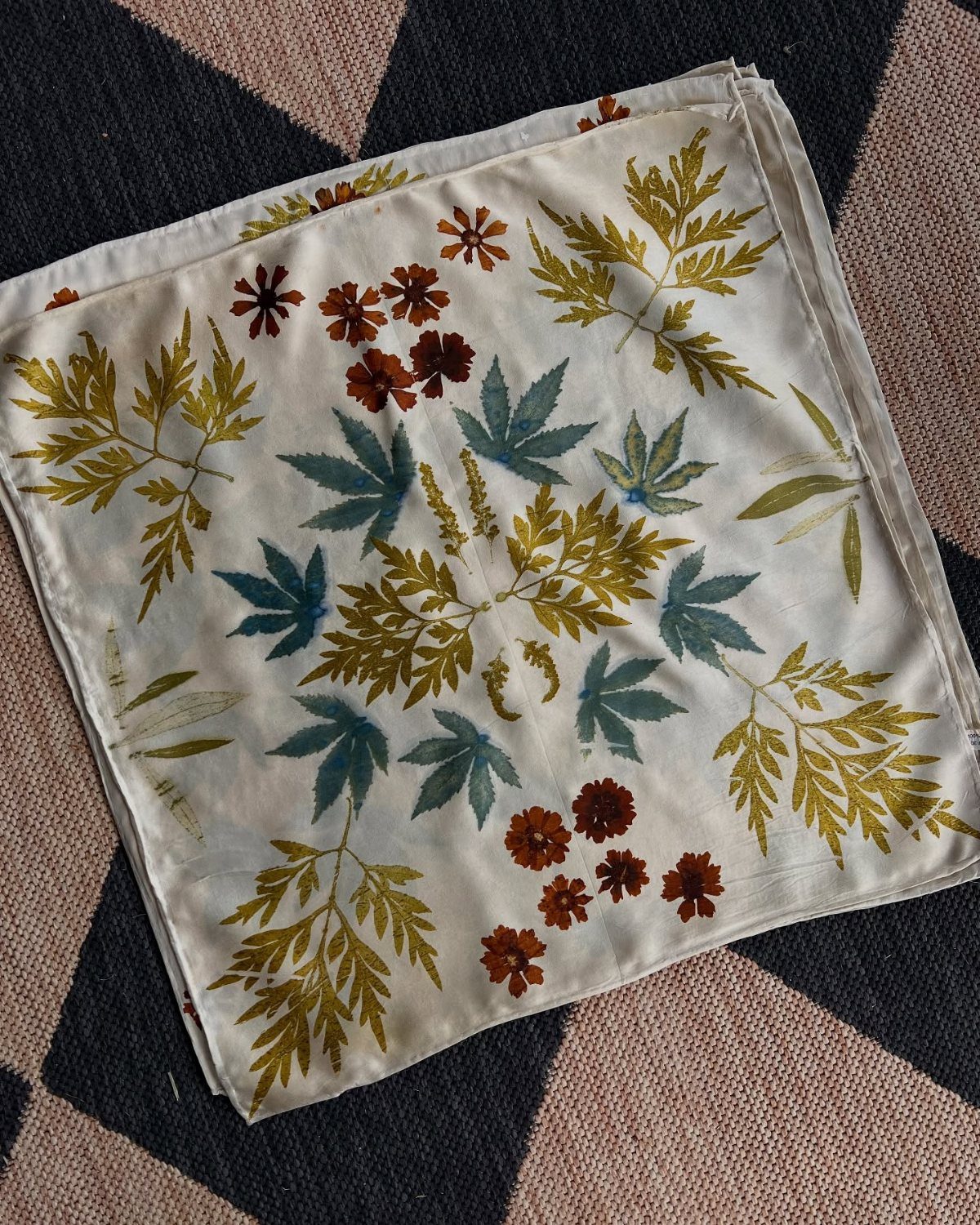 White fabric cloth with botanical leaf and flower prints on a patterned rug