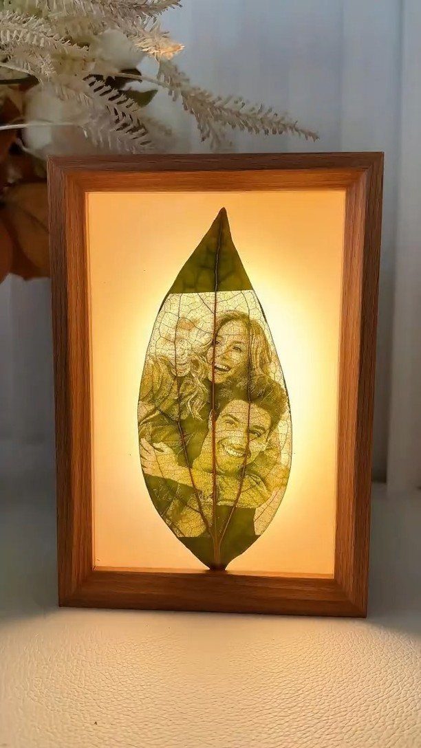 Backlit green leaf with an etched couple's portrait inside a wooden frame