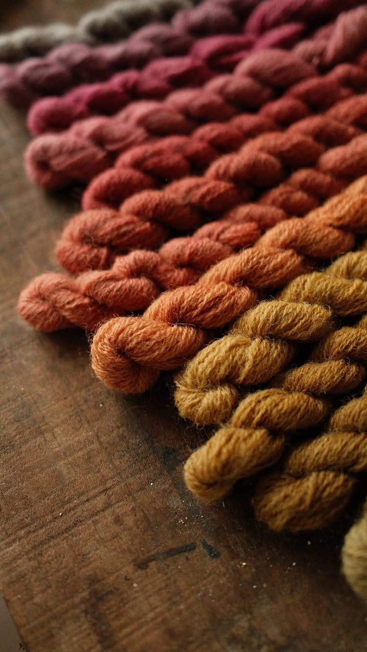 Twisted wool yarn hanks in earthy tones resting on a rustic wooden surface.