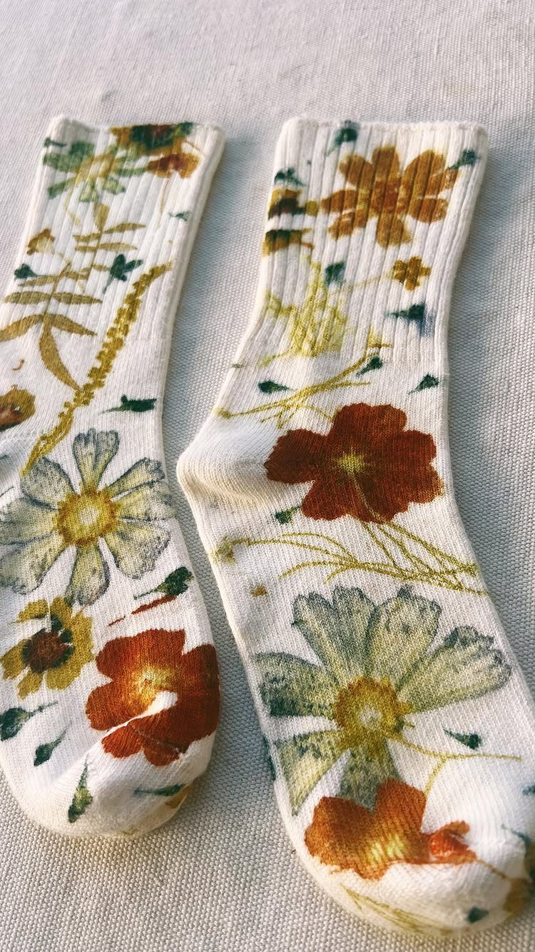 White ribbed socks with orange and green botanical flower prints on linen fabric.