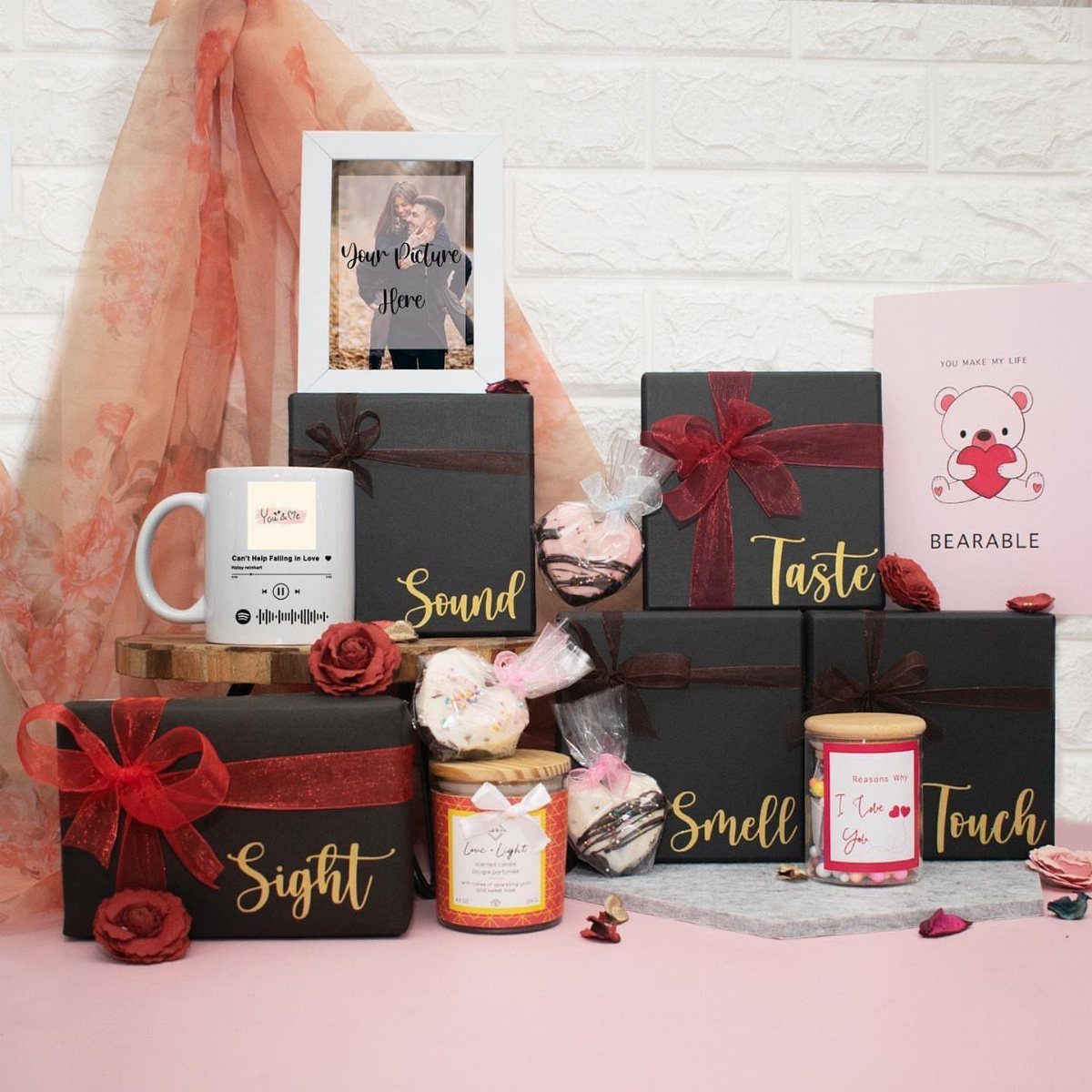 Five black gift boxes labeled by senses with treats, a mug, and roses.