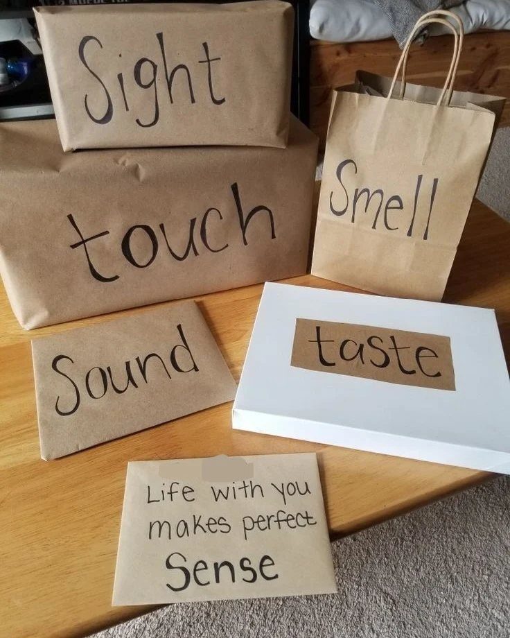 Five wrapped gifts labeled with the five senses on a wooden table.
