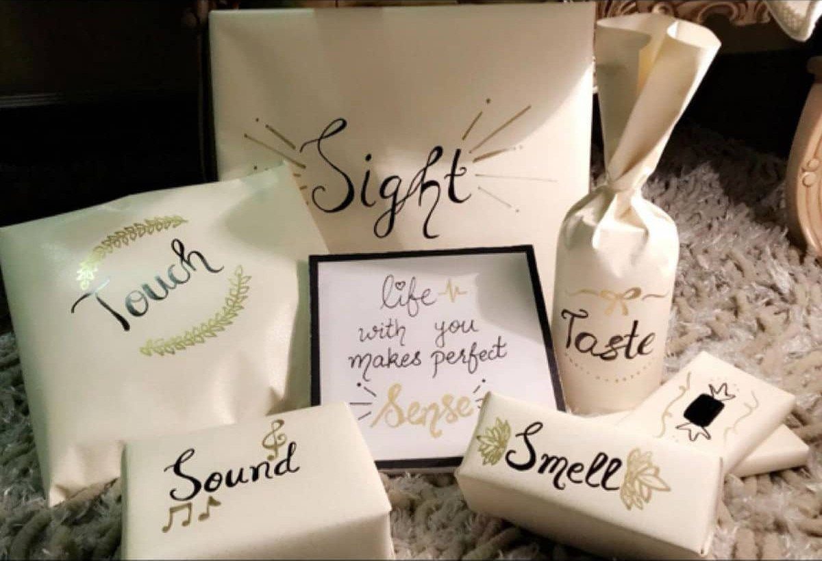 Five white wrapped gifts labeled with the five senses surrounding a framed quote.