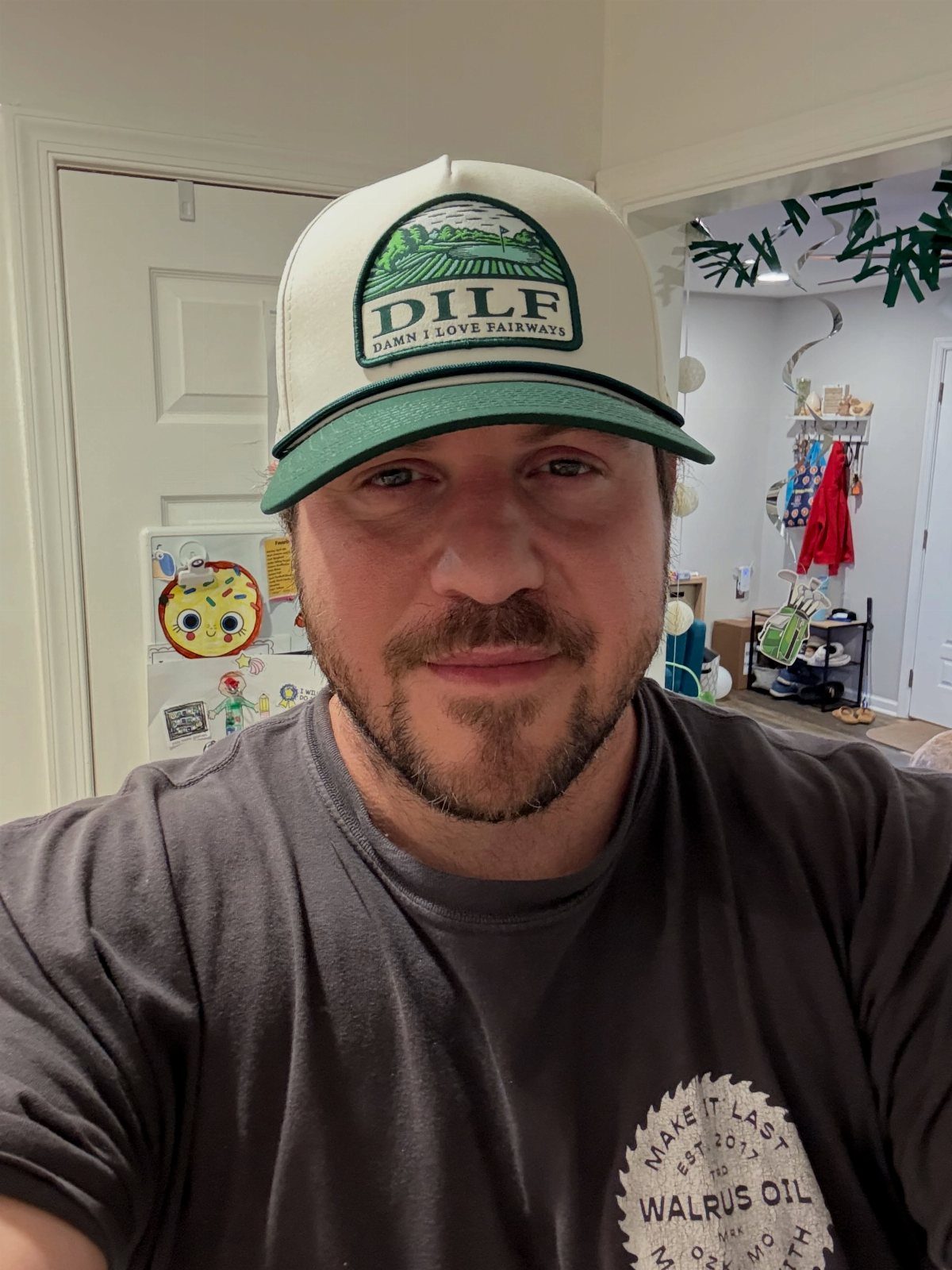 Man wearing a white and green golf hat with a funny DILF acronym.