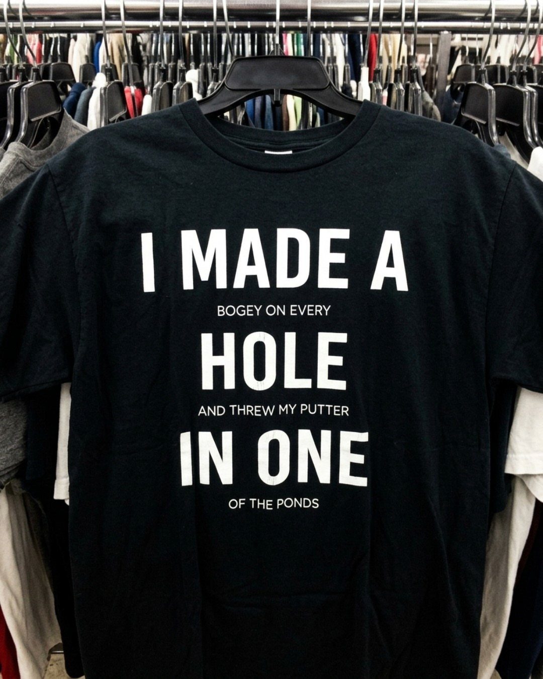 Black t-shirt with a funny golf joke printed in white text on a rack