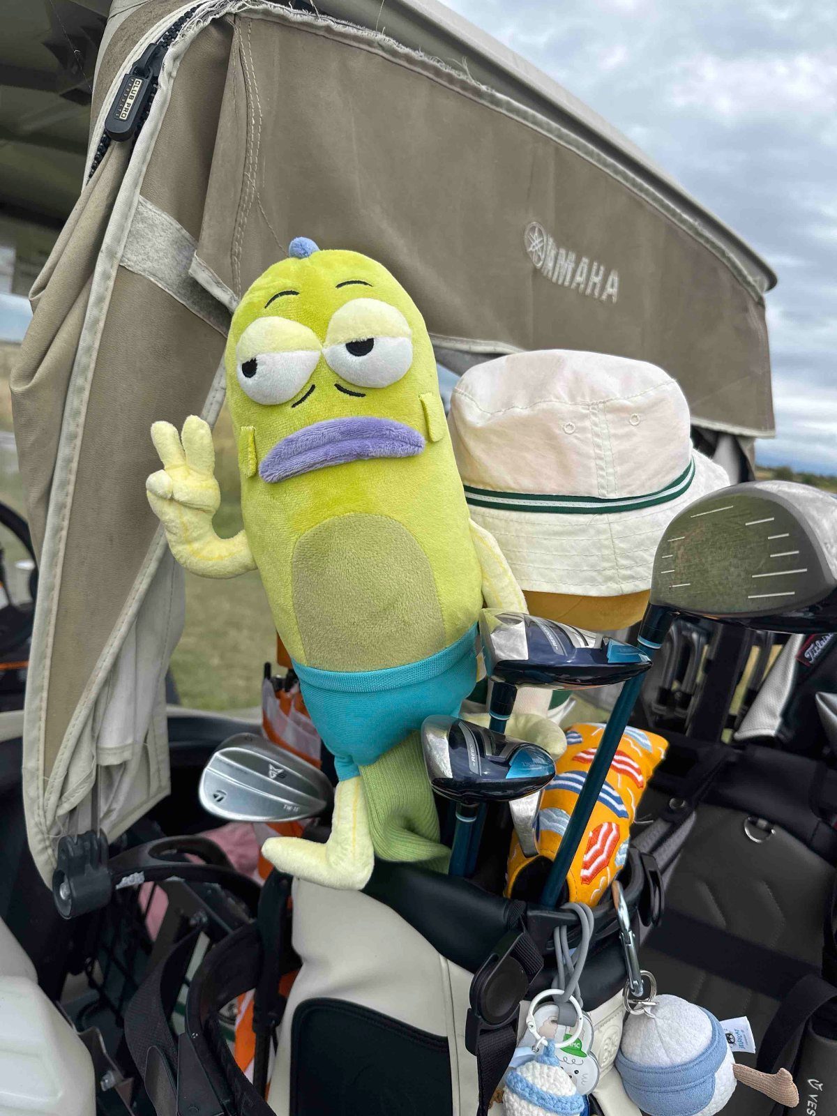 Grumpy lime green plush golf club headcover sitting in a golf bag