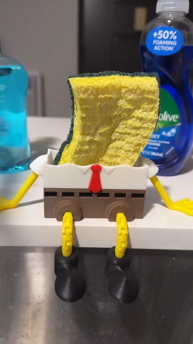 Sponge in a funny man-shaped holder with a red tie and black shoes.