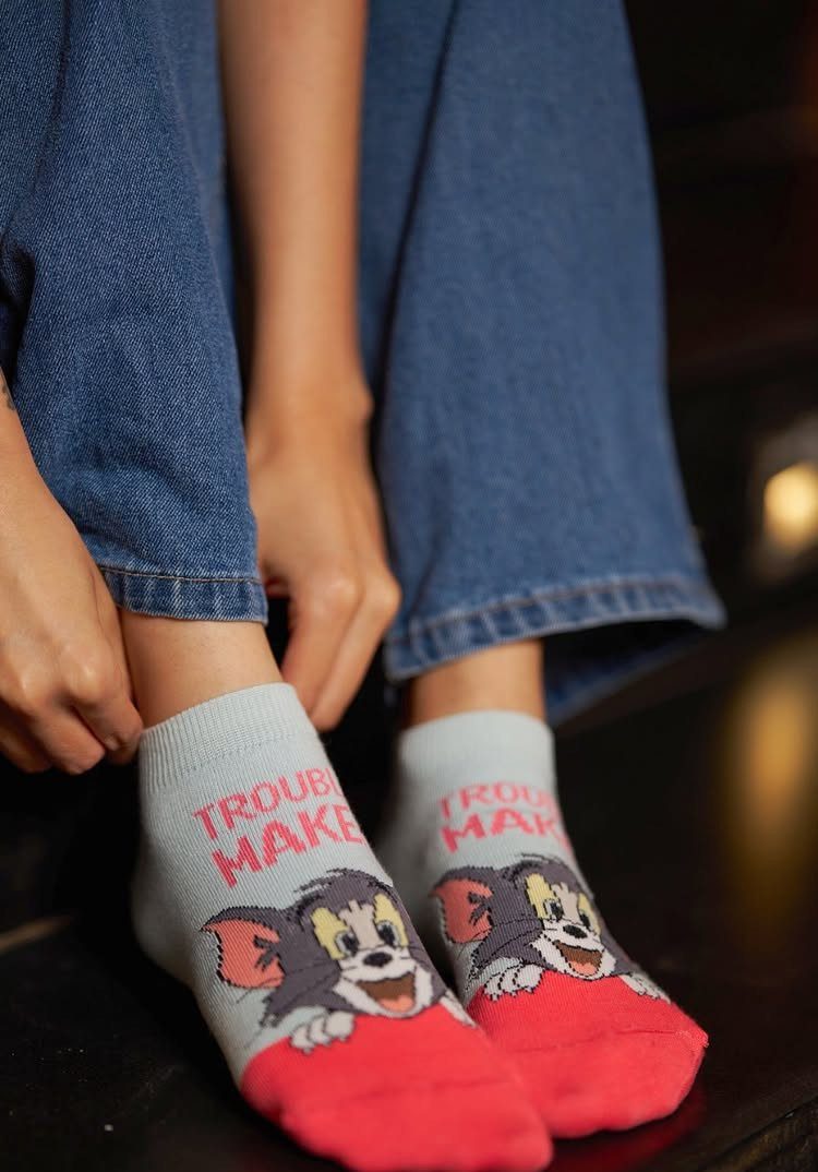 Grey socks with a cartoon cat and red Trouble Maker text on feet.