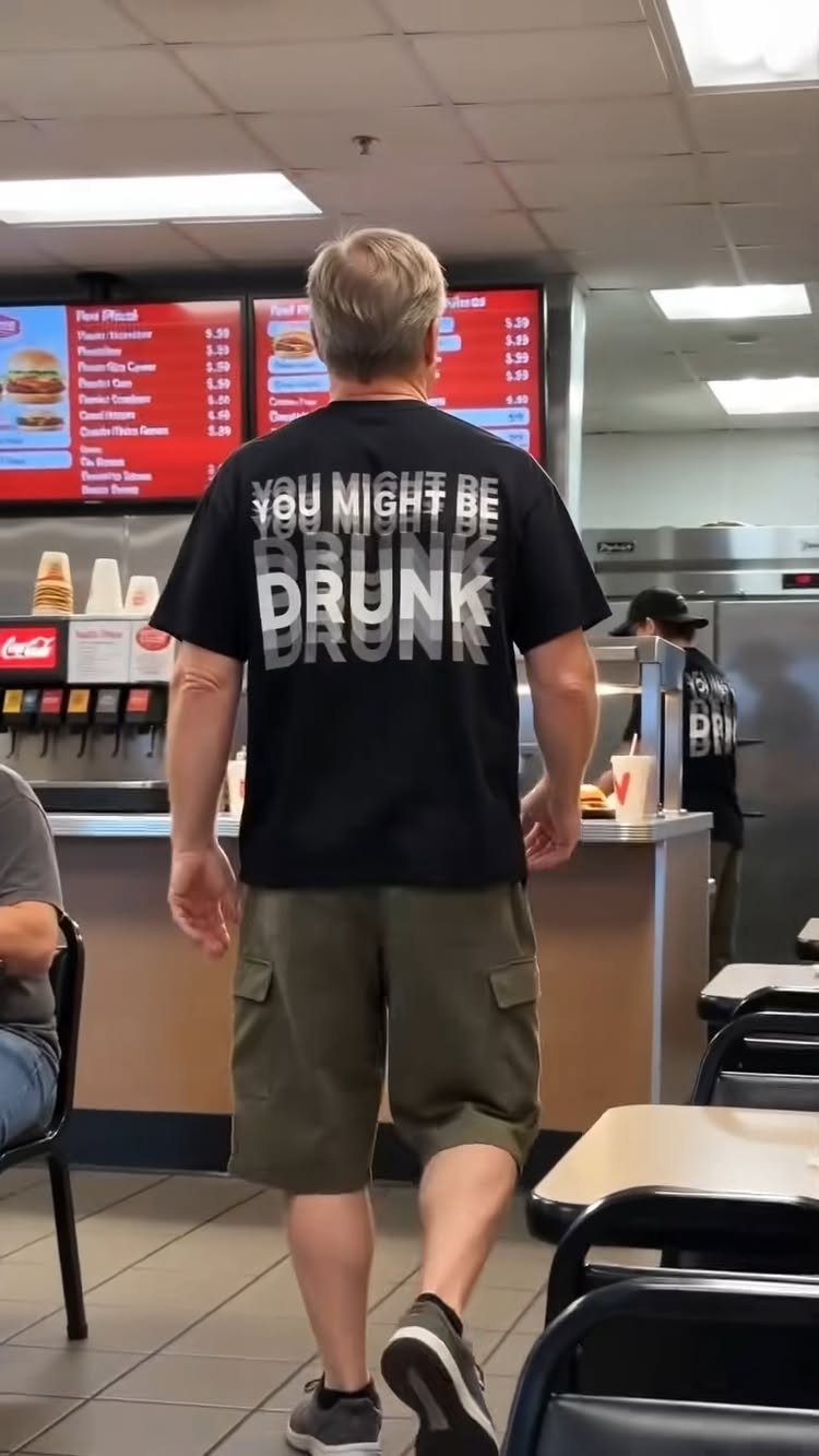 Man wearing a black t-shirt with funny text standing in a restaurant