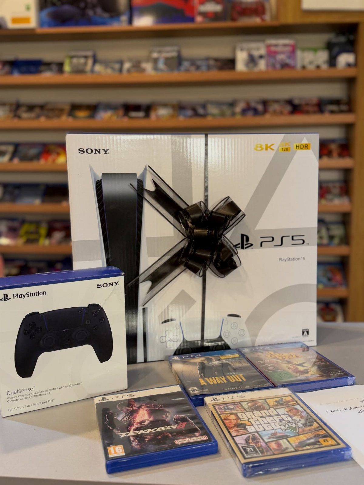 PlayStation 5 console box with black bow, controller, and several game cases.