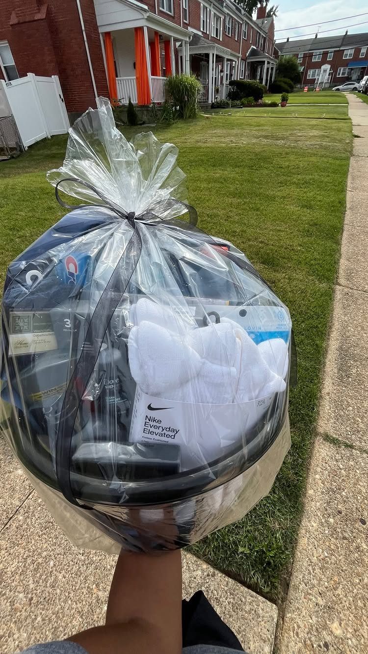 Gift basket with a blue helmet and white Nike shirt wrapped in cellophane.