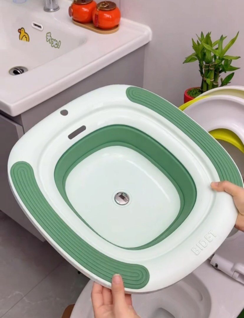 White and green plastic sitz bath basin held over a bathroom toilet.
