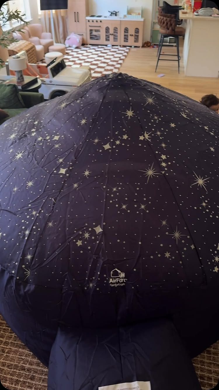Dark blue inflatable air fort with gold stars in a living room setting.