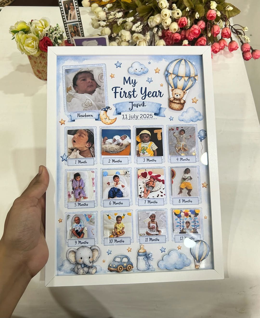 White photo frame displaying a baby's first year monthly growth photo collage.