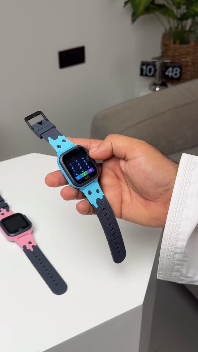 Blue and pink digital smartwatches held by a person over a white table