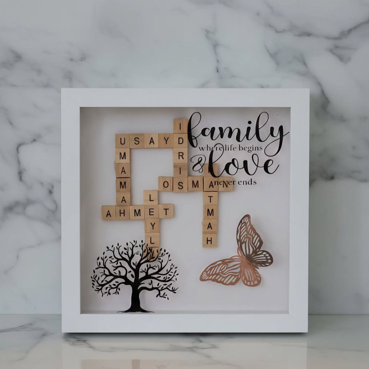 White shadow box with wooden name tiles, a black tree, and family text.