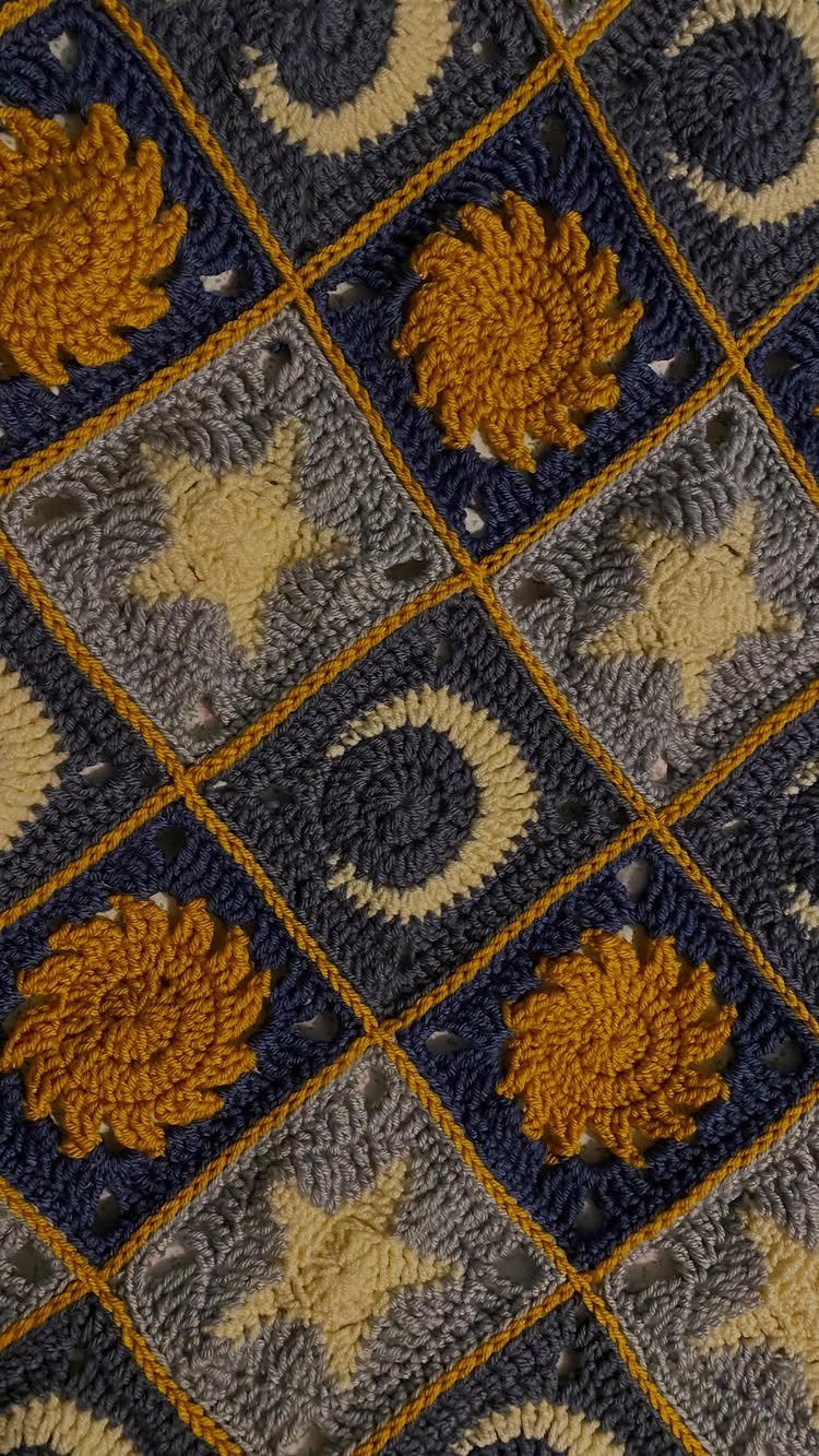 Crochet blanket with yellow suns, grey stars, and crescent moon patterns.