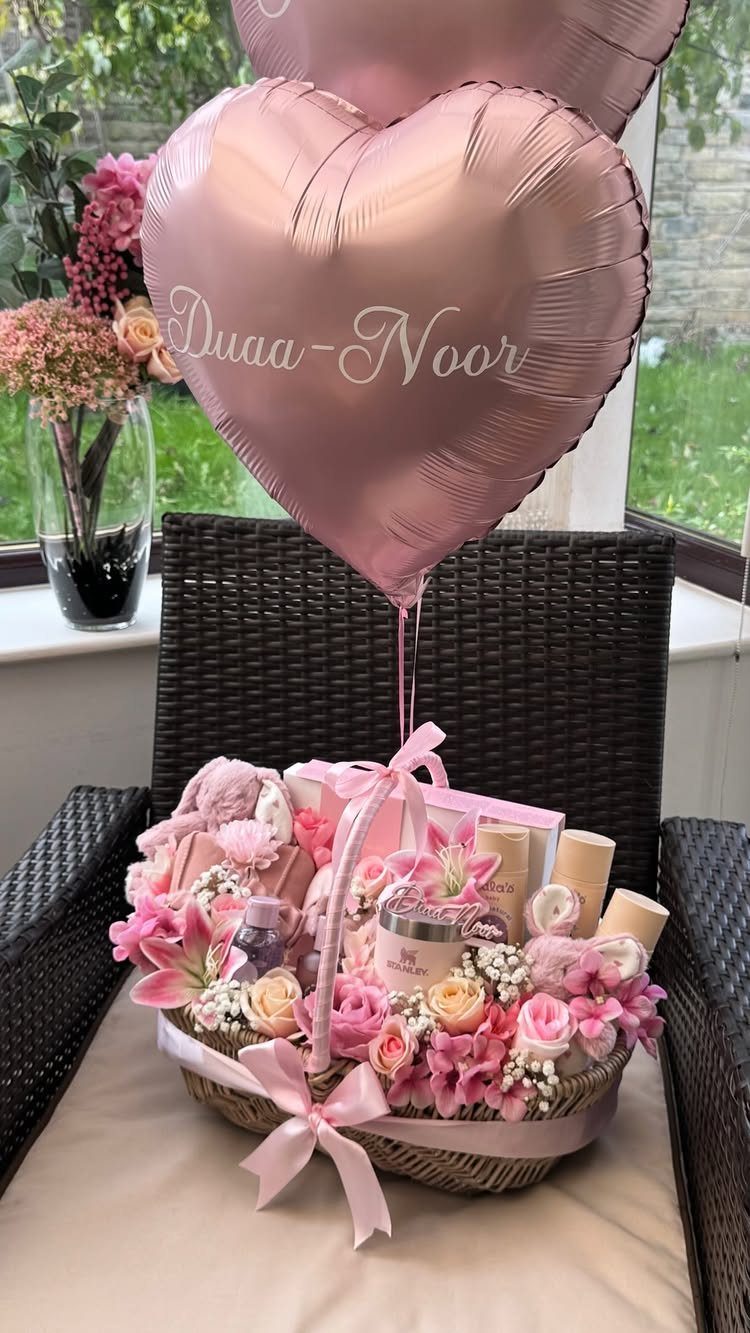 Wicker gift basket with pink flowers and skincare products under a heart balloon.