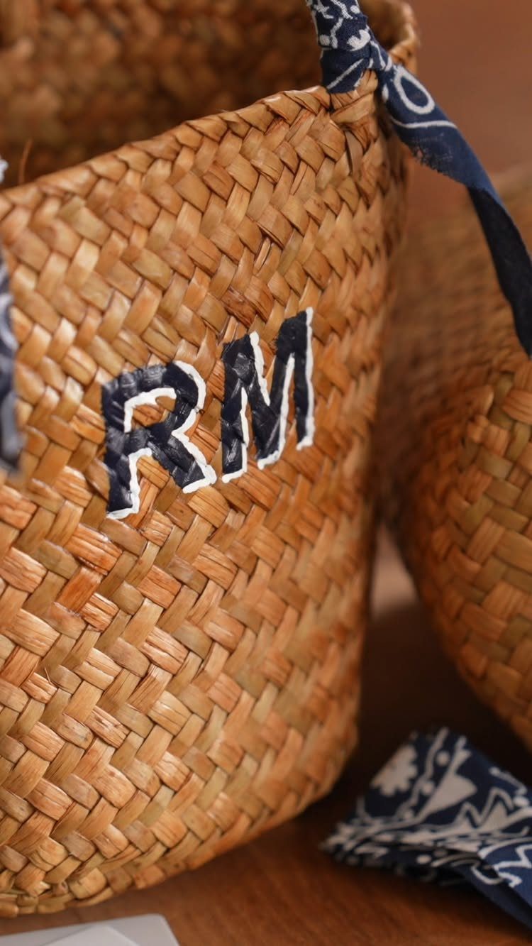 Woven straw bag with personalized RM initials and a blue patterned scarf.