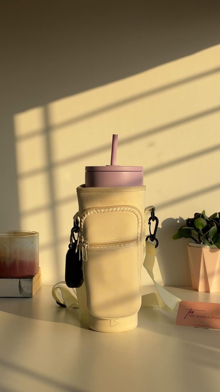 Cream fabric water bottle carrier holding a purple tumbler on a white table