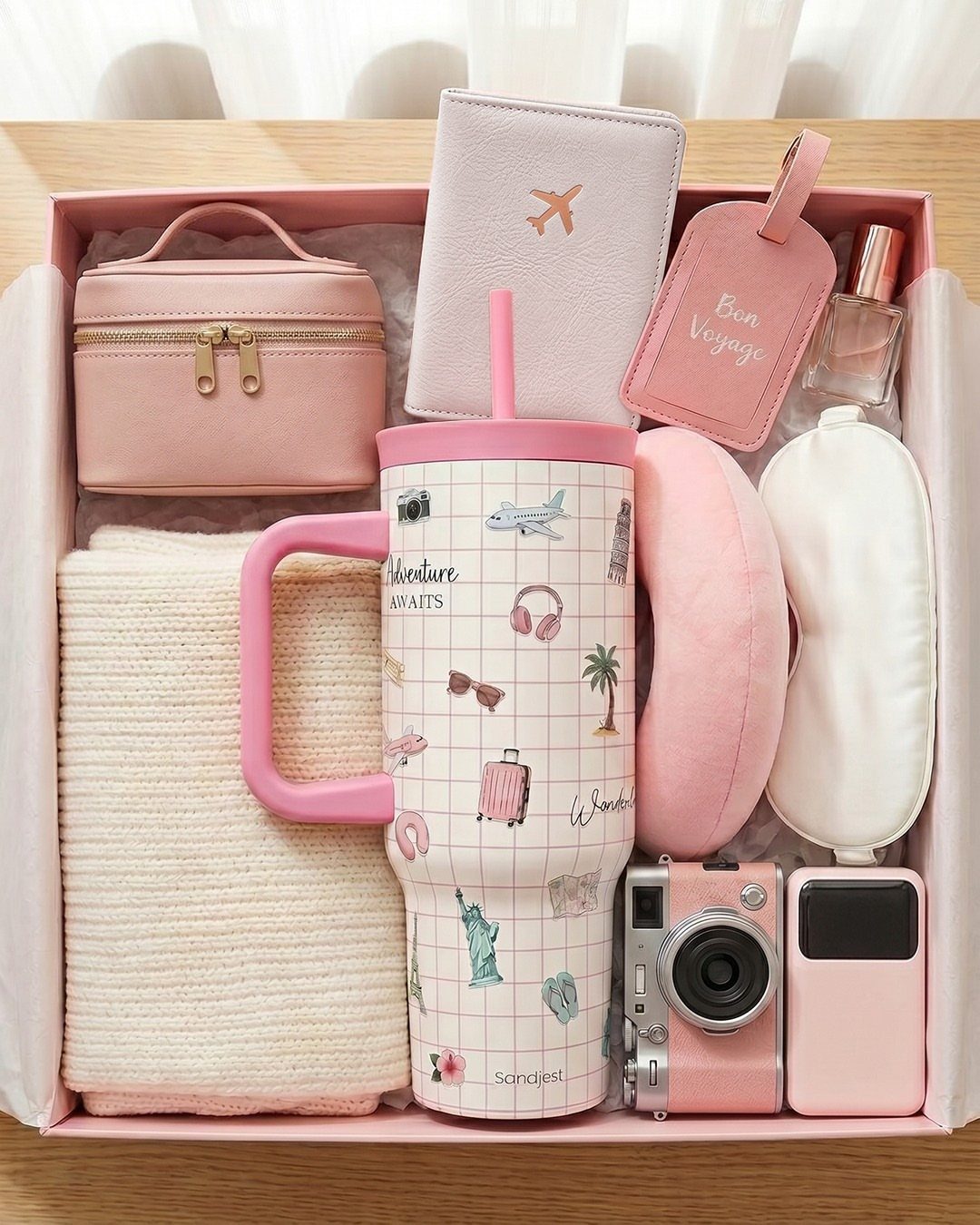 Pink travel gift set with tumbler, camera, passport holder, and neck pillows in box