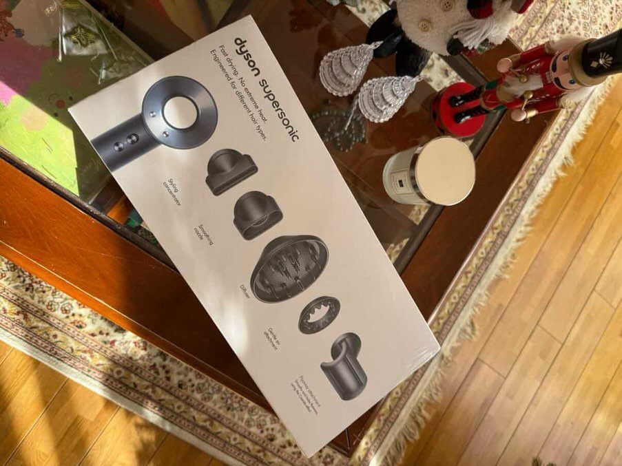 Dyson Supersonic hair dryer box on a glass table with holiday decorations.