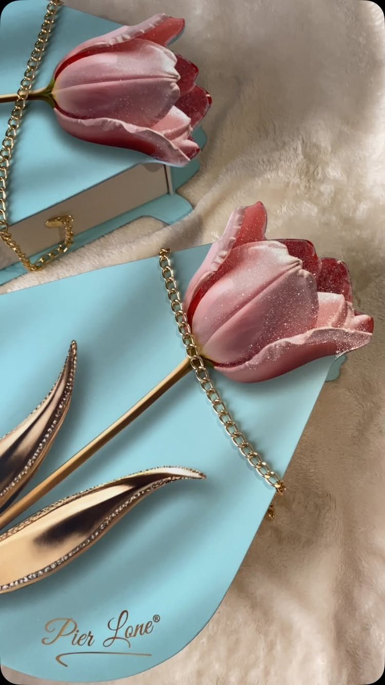Light blue clutches with 3D pink tulip accents and gold chains on white fur.