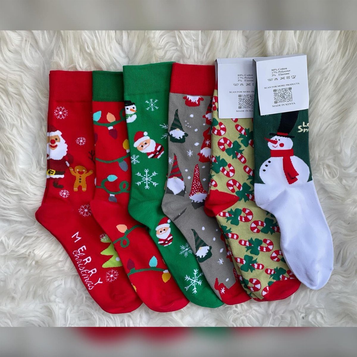 Christmas-themed socks with holiday patterns laid out on a white faux-fur background.