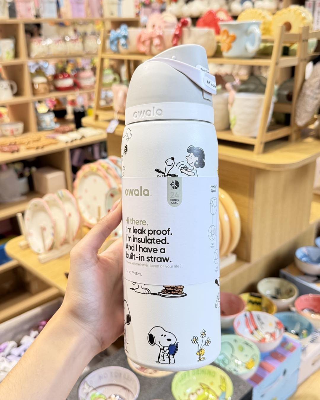 White Owala insulated water bottle with Peanuts characters held in a store setting
