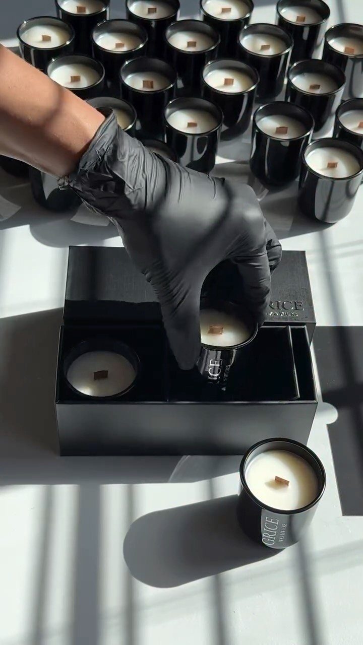 Hand in black glove placing a black candle into a black gift box