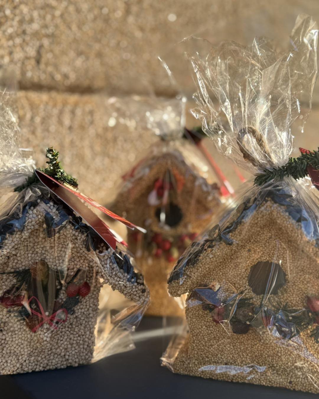 Seed-based bird feeders shaped like small houses wrapped in clear cellophane packaging.