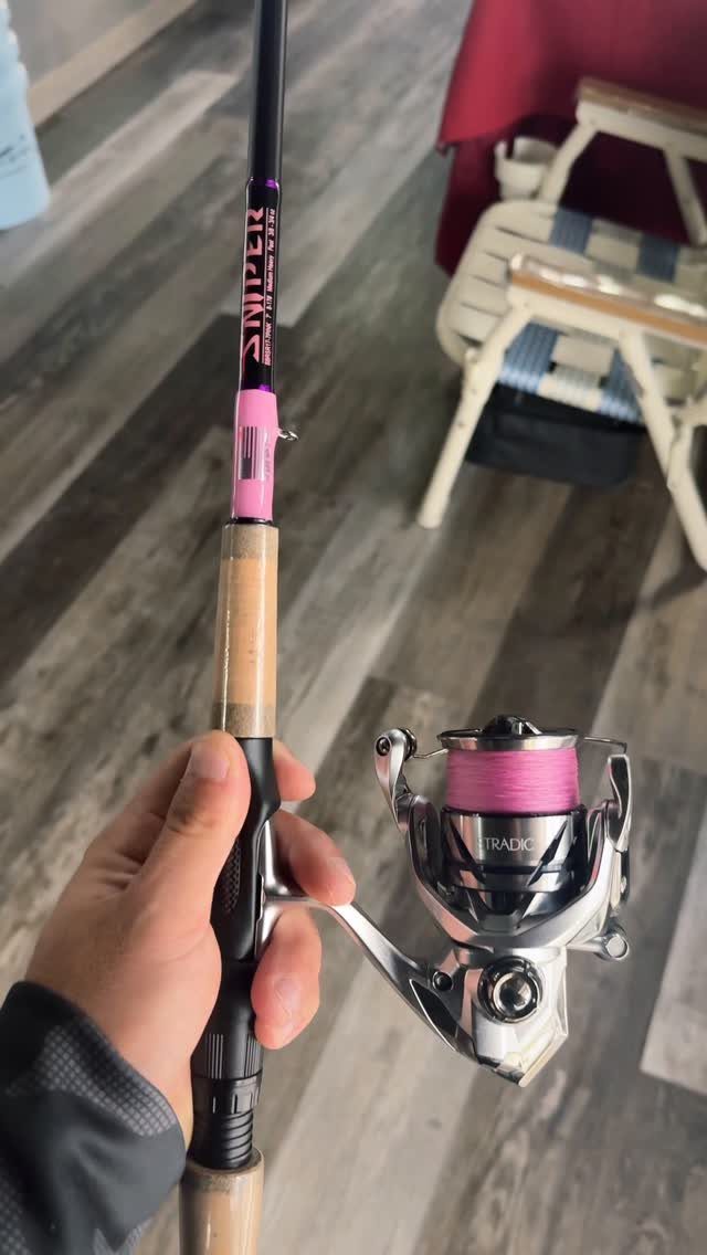 Fishing rod and reel with pink line held by a person's hand.