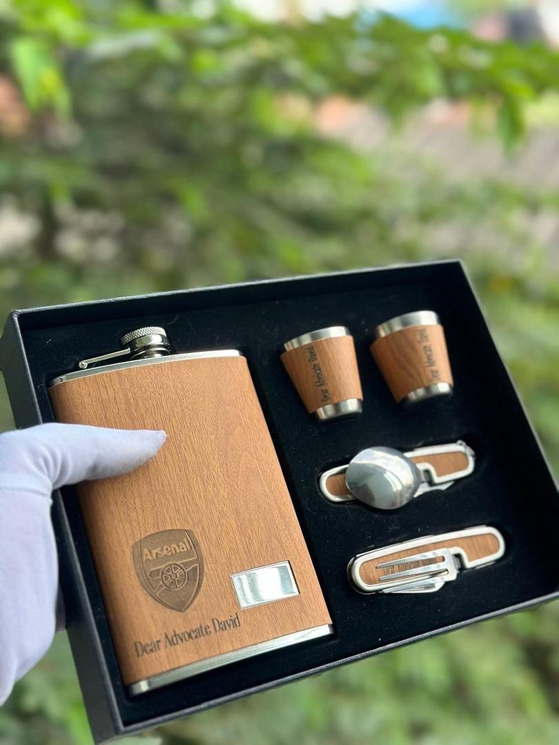 Wooden flask and barware set in a black gift box held by hand.