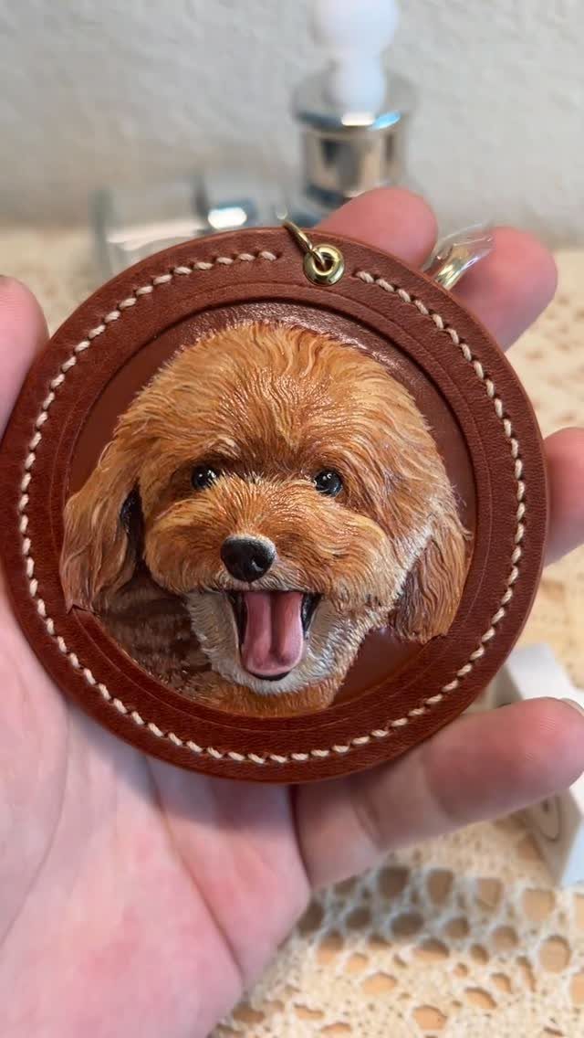 Circular brown leather keychain featuring a realistic painting of a fluffy brown dog.