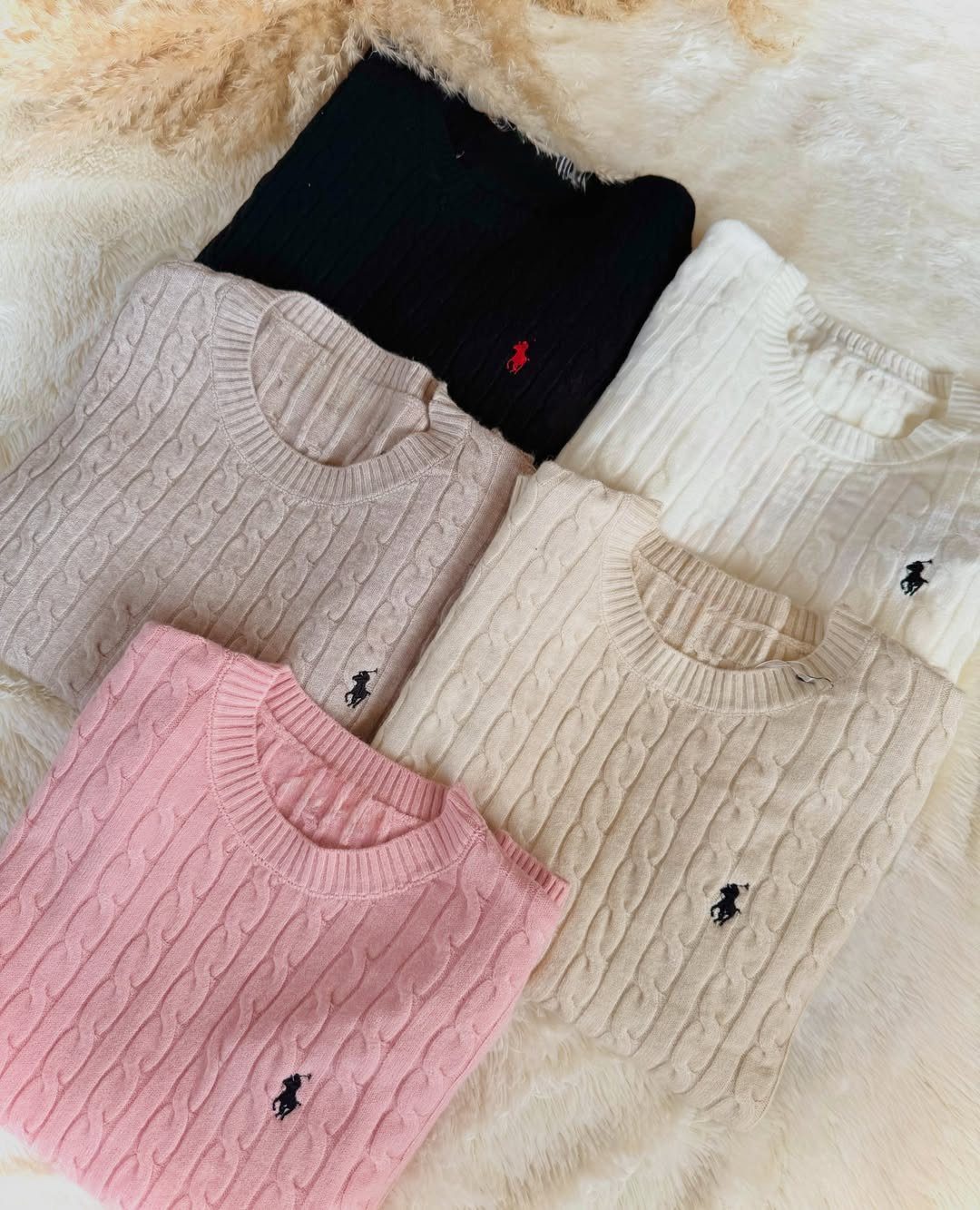 Cable-knit sweaters in pink, beige, tan, white, and black on white faux fur.
