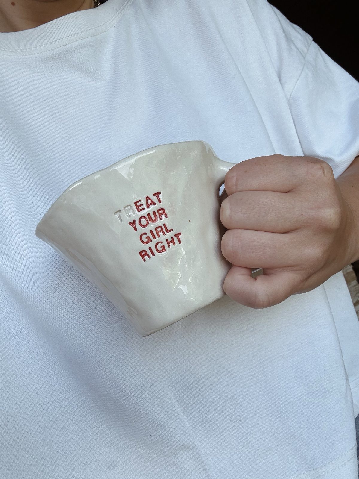 White ceramic mug with red text saying Treat Your Girl Right held by person