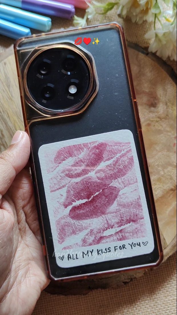 Black smartphone in a clear case featuring red lipstick kiss marks and romantic text.