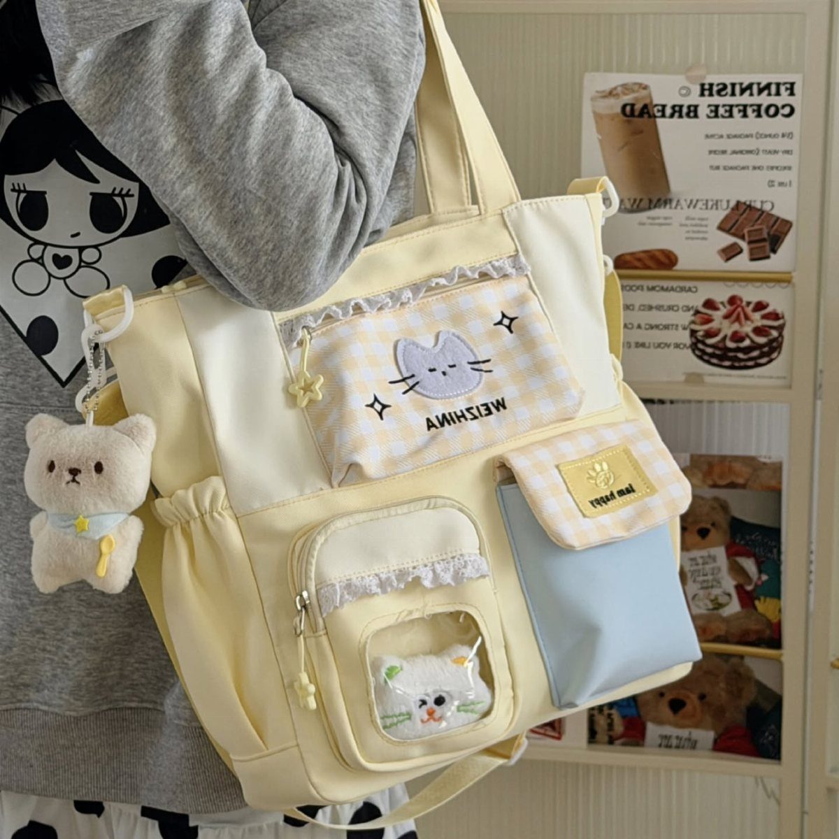 Pale yellow tote bag with cat designs and a small bear charm.
