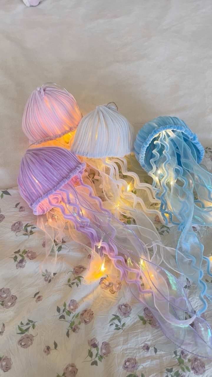 Jellyfish-shaped lamps in purple, white, and blue glowing on floral fabric.