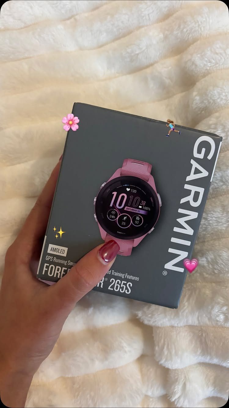 Pink Garmin fitness tracker on its grey packaging held by a hand.
