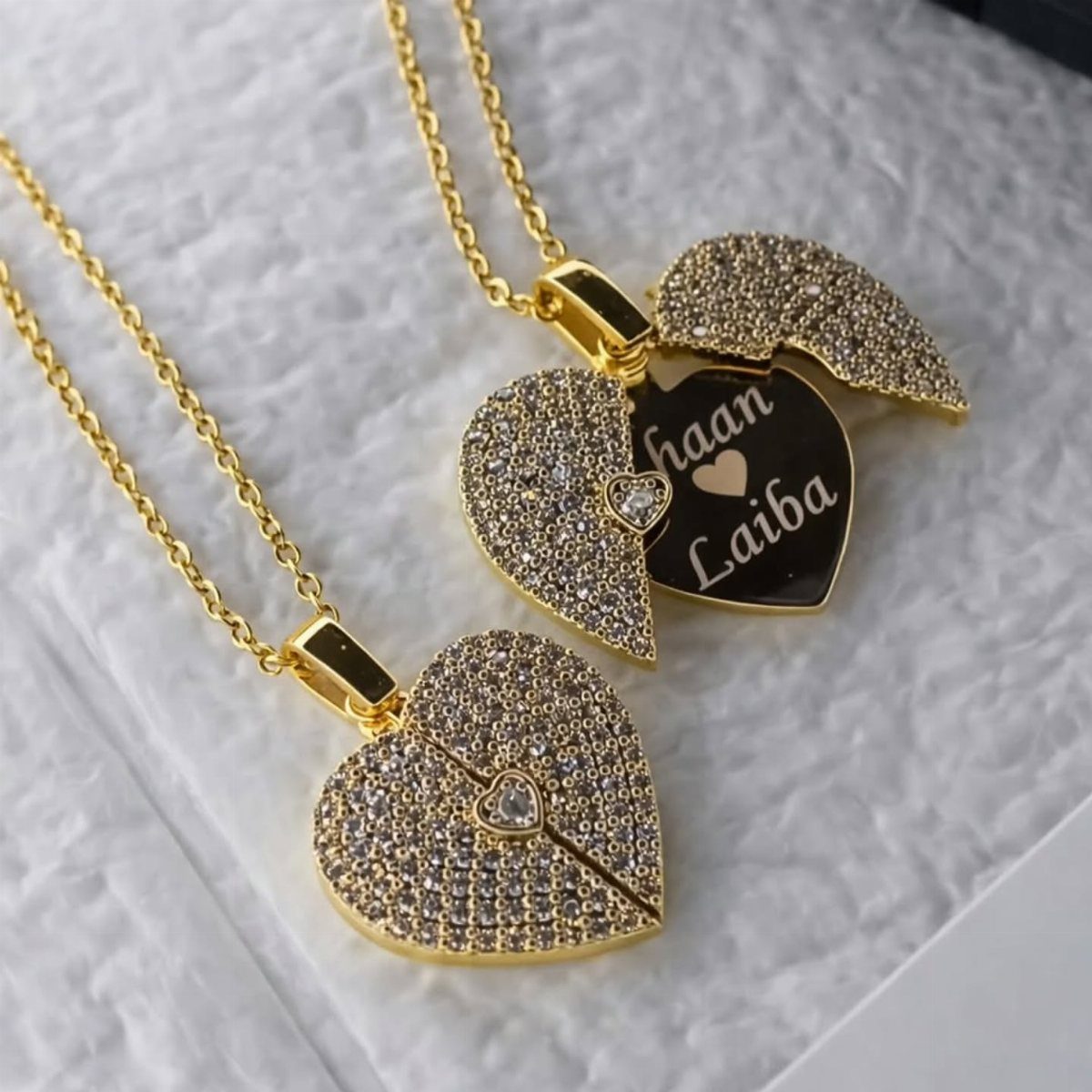 Gold heart necklaces with crystals, one open showing personalized names Haan and Laiba.